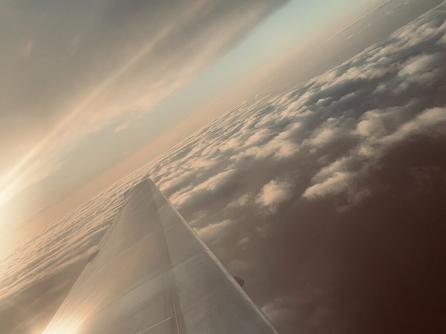 Vue d'une aile d'avion au-dessus des nuages au coucher du soleil