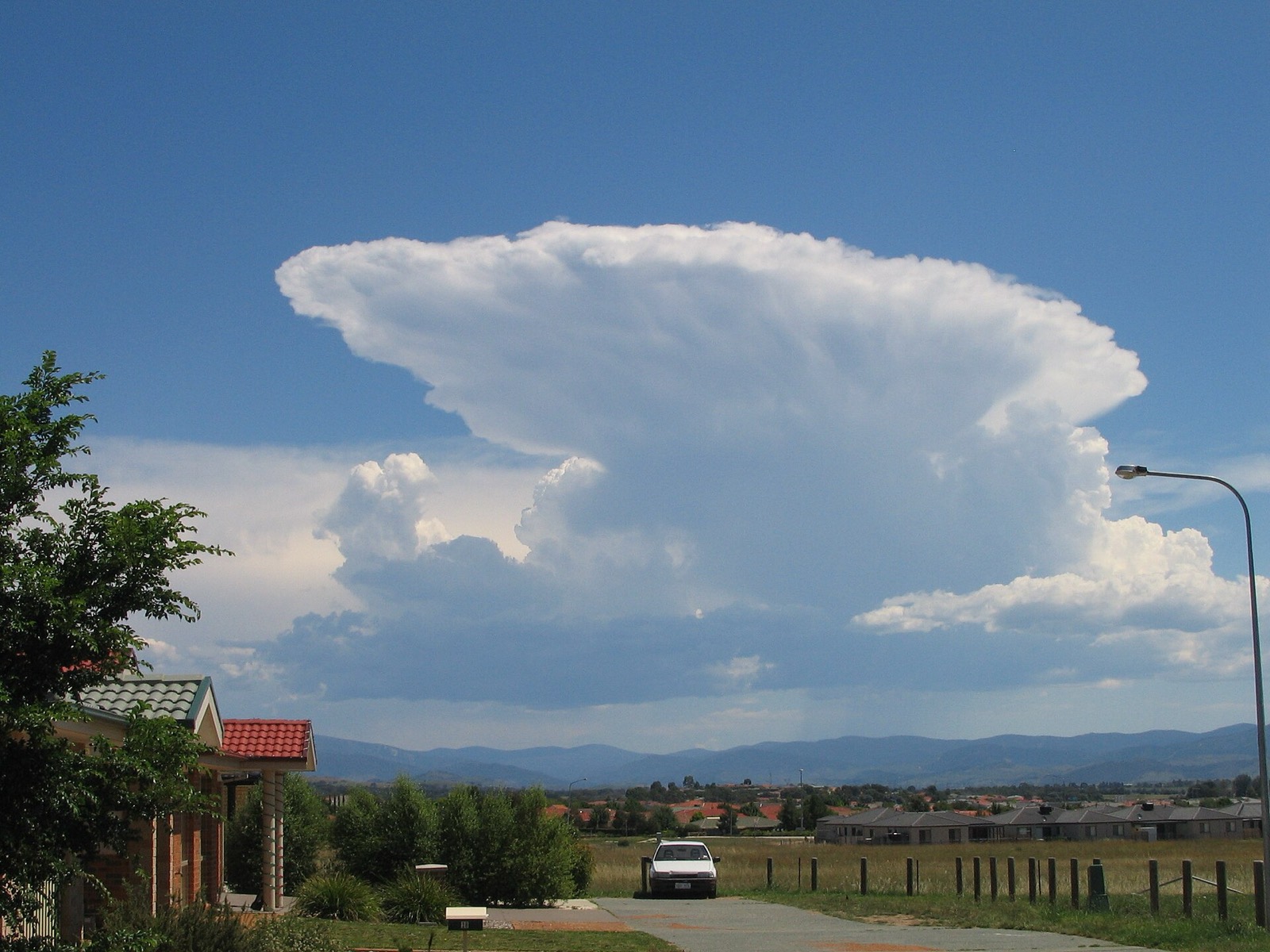 Cumulonimbus en enclume dominant un paysage de banlieue par temps clair